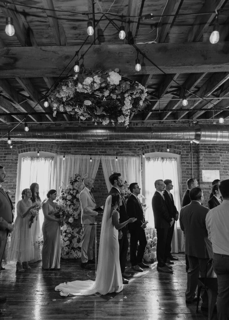 Bride, groom, wedding party, and guests worshiping together during ceremony