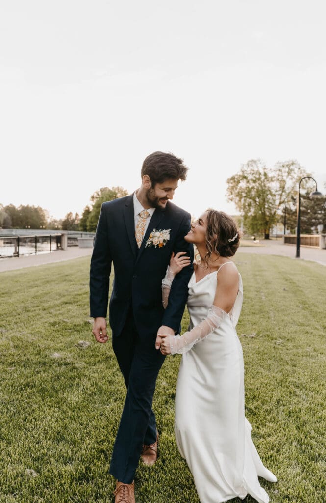 Bride and groom walking hand in hand during golden hour at their Michigan wedding at Record Box Loft.